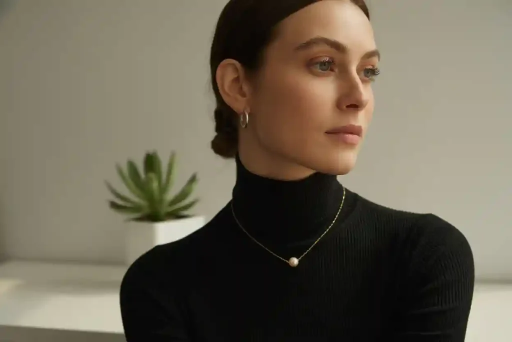 femme en pull noir avec boucles d'oreilles et collier