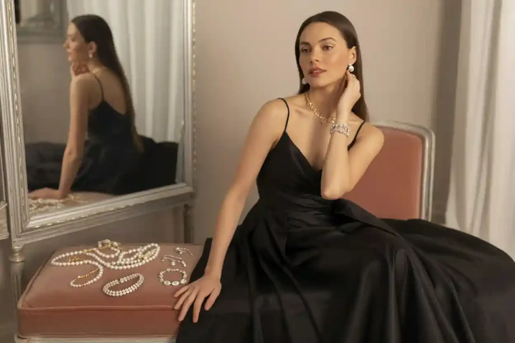 femme qui porte ue robe en satin noire et un ncollier de perles