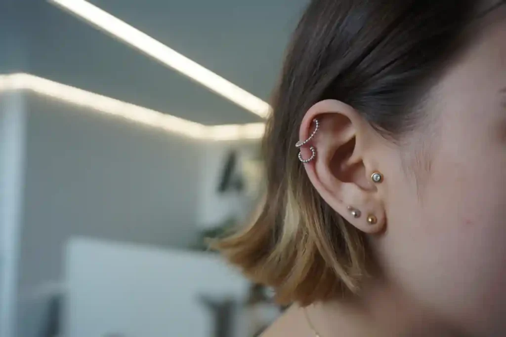 gros plan sur oreille avec plusieurs boucles d'oreilles
