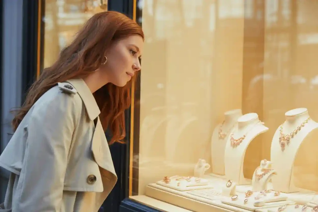 femme devant une vitrine de bijouterie en train de regarder des bijoux en argent rose