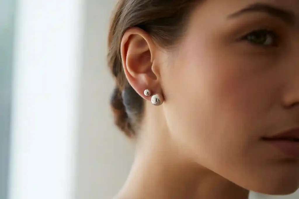 femme qui porte 2 clous d'oreilles boules sur le même lobe