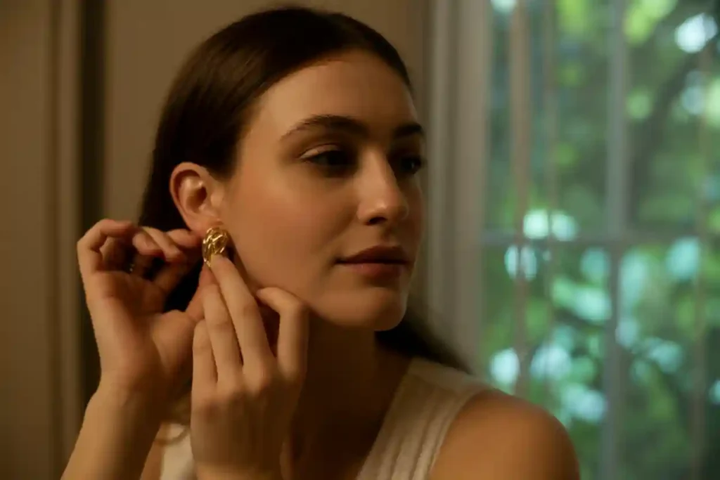 femme qui retire ses boucles d'oreilles en plaqué or avant d'aller dormir