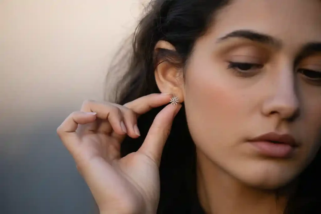 femme qui retire sa puce d'oreille en forme d'étoile