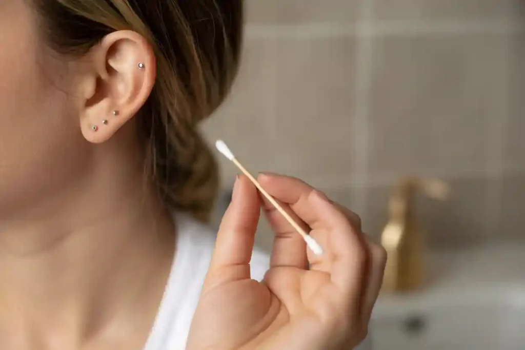 gros plan oreille femme avec clous et coton tige