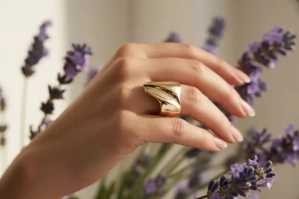 main de femme qui porte une bague contemporaine en plaqué or