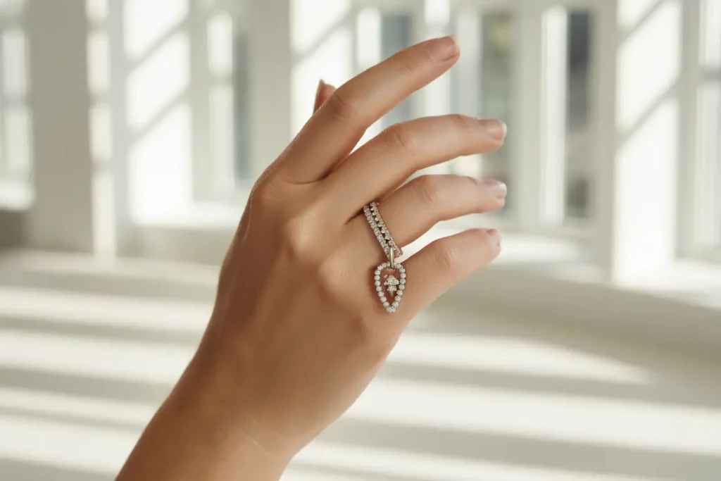 main qui porte une bague avec breloque en forme de feuille et cristaux